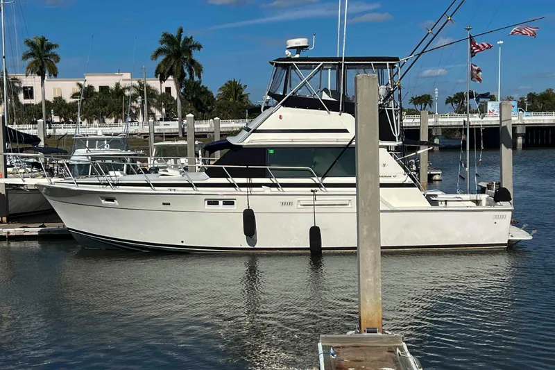 The Image of 1986 Bertram 42 Convertible yacht docked in a marina under a clear blue sky. - 0