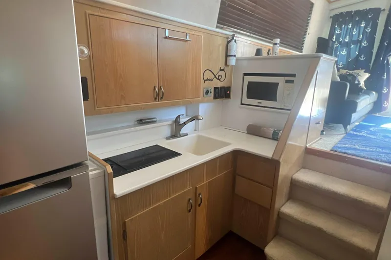 Slide: The Image of 1986 Bertram 42 Convertible yacht kitchen with sink, microwave, and wooden cabinets. - 10