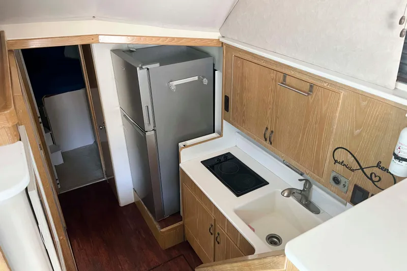 Slide: The Image of 1986 Bertram 42 Convertible yacht kitchen with wood cabinets, sink, stove, and refrigerator. - 11