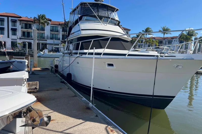 Slide: The Image of 1986 Bertram 42 Convertible yacht docked at marina with waterfront buildings. - 3