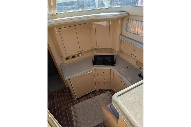 Slide: The Image of 2000 Sea Ray 420 Aft Cabin yacht kitchen with stove, sink, and wooden cabinetry. - 11
