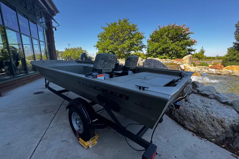 Slide: The Image of 2026 Tracker Grizzly 1754 SC boat on trailer, parked outdoors near rocks and trees. - 2
