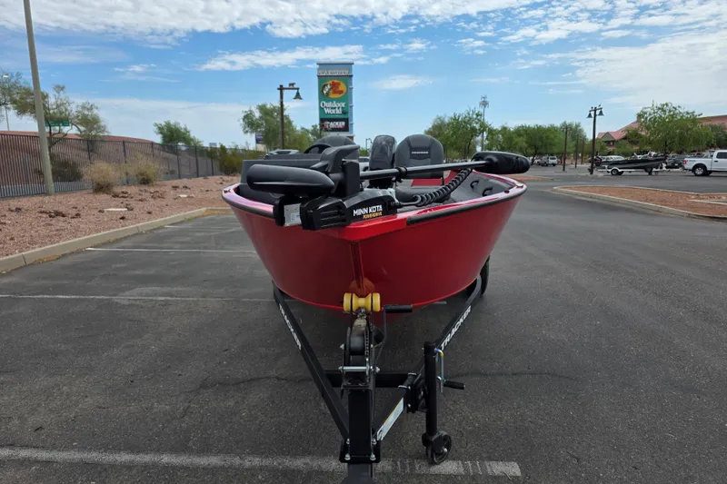 Slide: The Image of 2026 Tracker Pro Guide V-16 SC boat in parking lot, red exterior, clear sky background. - 2