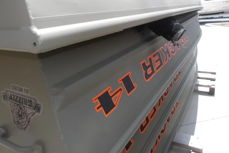 The Image of 2026 Tracker Grizzly 14 Jon boat with bold orange lettering and Grizzly logo. - 0