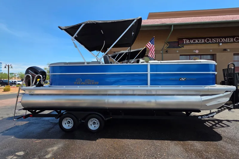 The Image of 2026 Sun Tracker Party Barge 22 DLX pontoon boat with canopy, parked on trailer. - 0