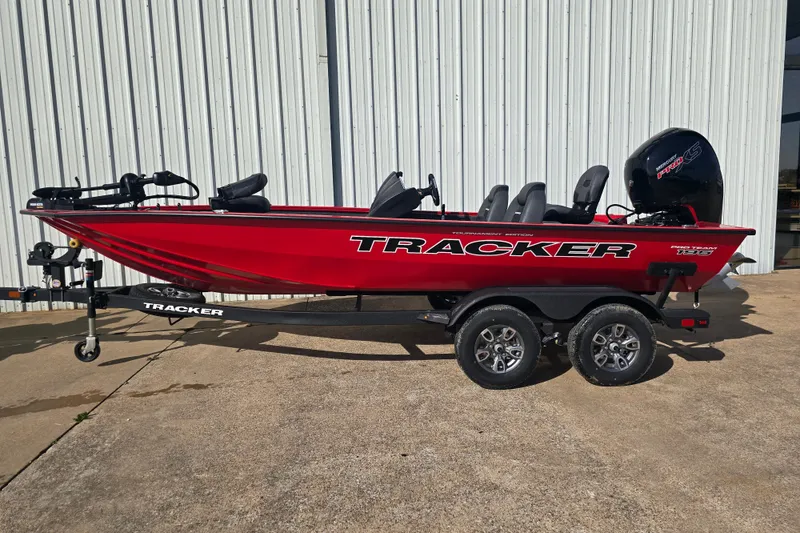 The Image of 2026 Tracker Pro Team 195 boat, red, on trailer, parked outside a building. - 0