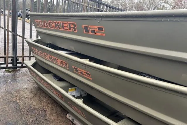 The Image of 2026 Tracker Grizzly 12 Jon boats stacked outdoors near a metal fence. - 0