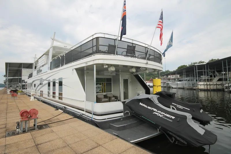 Slide: The Image of 2008 Sharpe 105 Custom Houseboat docked with jet skis, flags, and spacious deck. - 19