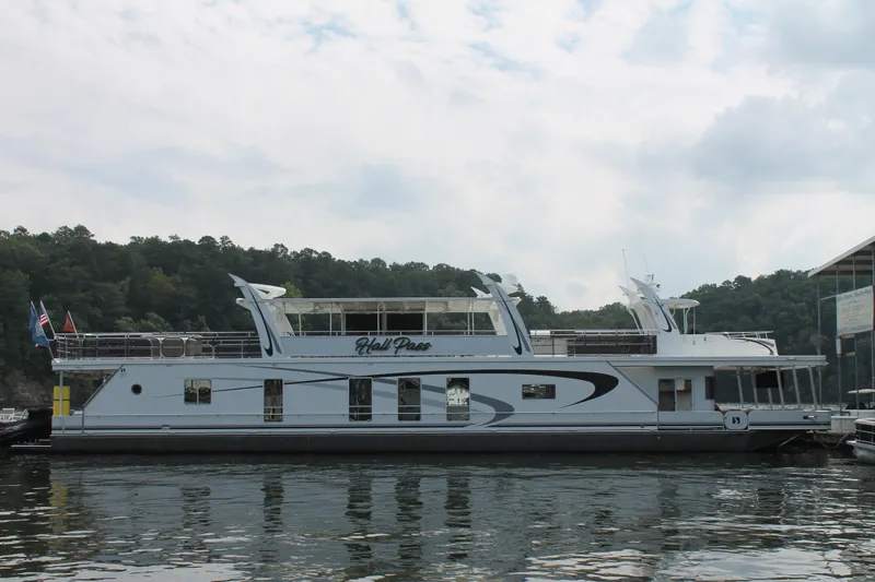 Slide: The Image of 2008 Sharpe 105 Custom Houseboat on calm water, surrounded by trees and cloudy sky. - 2
