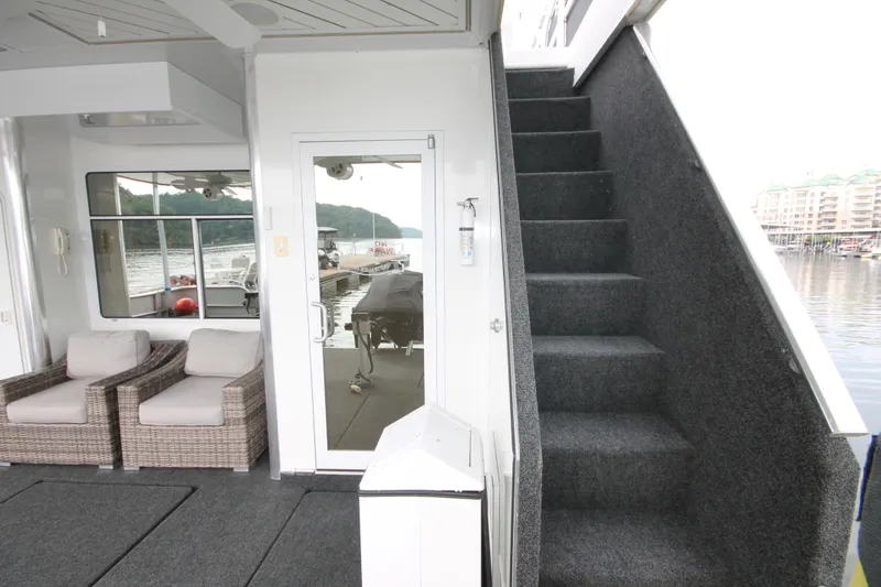 Slide: The Image of 2008 Sharpe 105 Custom Houseboat interior with stairs, wicker chairs, and lake view. - 24