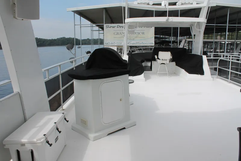 Slide: The Image of 2008 Sharpe 105 Custom Houseboat deck with covered seating and storage, docked by a serene lake. - 33