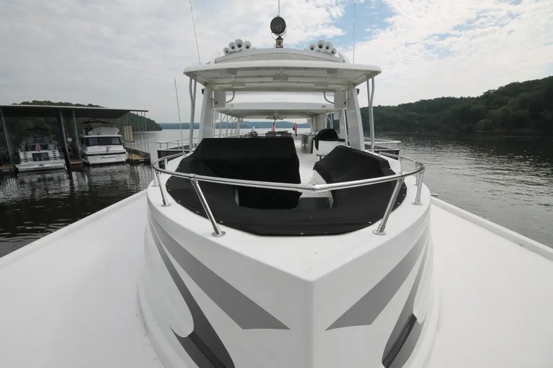 Slide: The Image of 2008 Sharpe 105 Custom Houseboat on a serene lake with docked boats nearby. - 39
