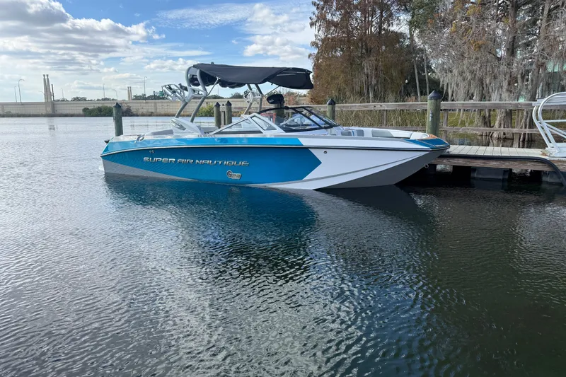 The Image of 2013 Nautique Super Air Nautique G23 Coastal Edition boat docked on calm water. - 0