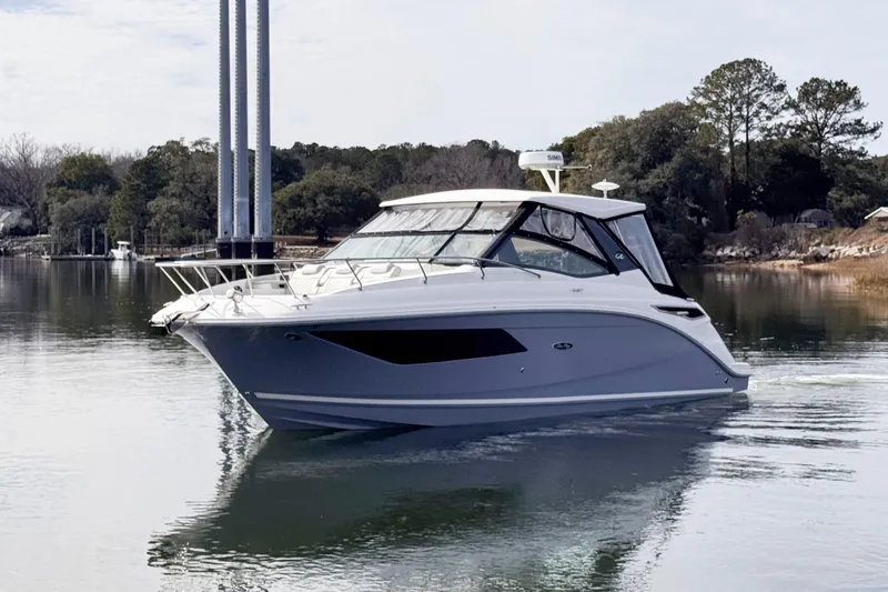 Slide: The Image of 2022 Sea Ray Sundancer 320 yacht on calm water, surrounded by trees. - 2