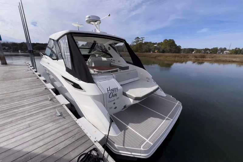 Slide: The Image of 2022 Sea Ray Sundancer 320 docked, rear view with open cockpit and serene water backdrop. - 28