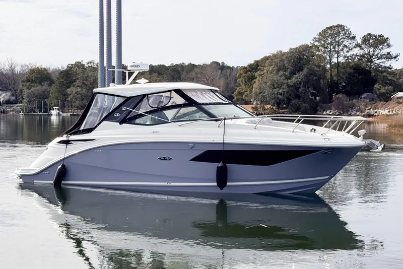 Slide: The Image of 2022 Sea Ray Sundancer 320 yacht on calm water, surrounded by trees. - 4