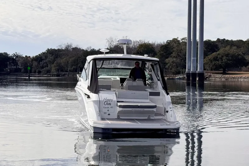 Slide: The Image of 2022 Sea Ray Sundancer 320 cruising on calm waters near a wooded shoreline. - 5