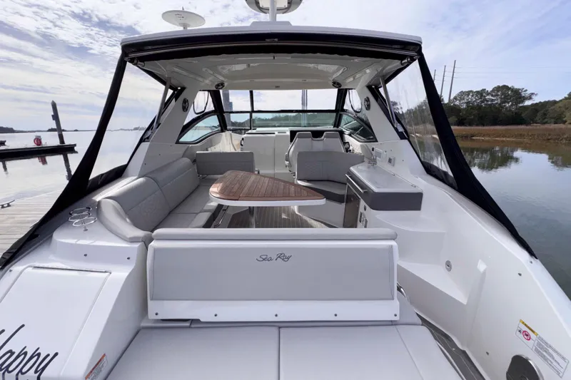 Slide: The Image of 2022 Sea Ray Sundancer 320 yacht interior with seating and table, docked by calm waters. - 7
