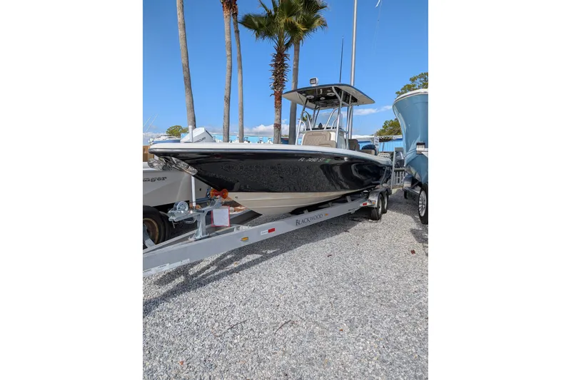The Image of 2012 Blackwood 27 boat on trailer, parked outdoors with palm trees in background. - 0