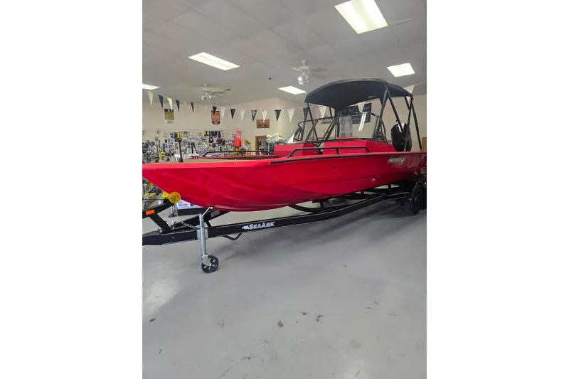 Slide: The Image of 2026 SeaArk Protege 240 boat with red exterior and black canopy, parked outside dealership. - 2