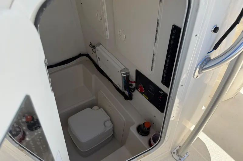 Slide: The Image of 2021 Sailfish 242 CC boat interior with compact toilet and control panel. - 15