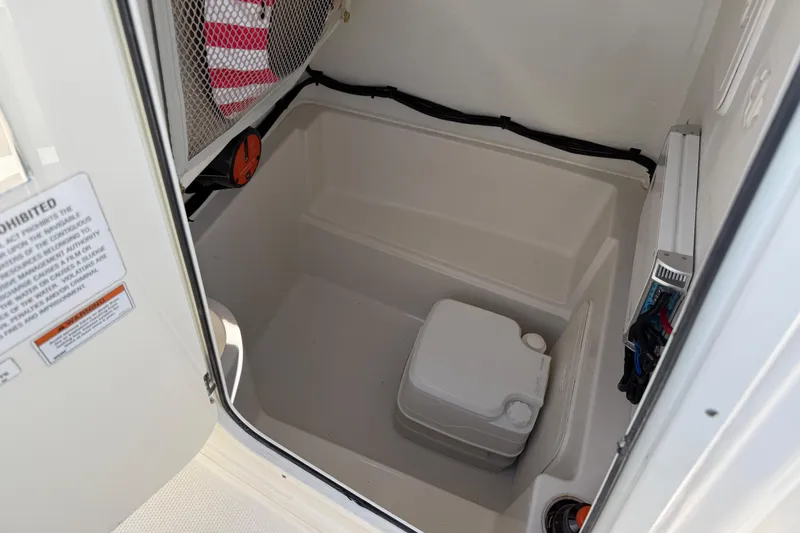 Slide: The Image of 2021 Sailfish 242 CC boat interior storage compartment with portable toilet. - 16