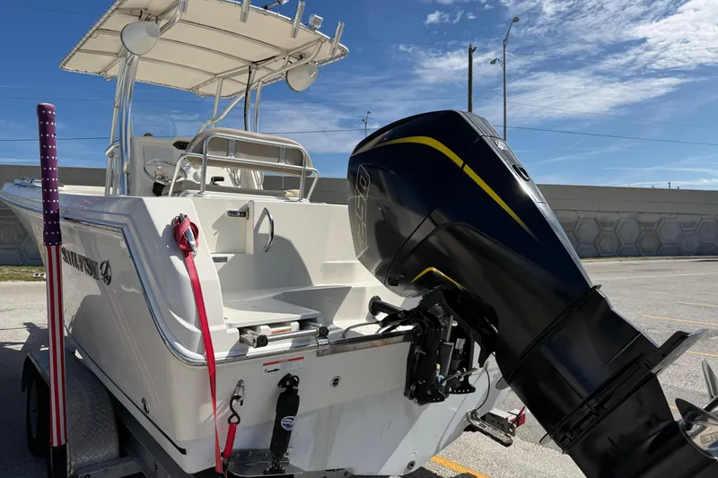 Slide: The Image of 2021 Sailfish 242 CC boat with outboard motor, parked on a trailer under clear skies. - 5