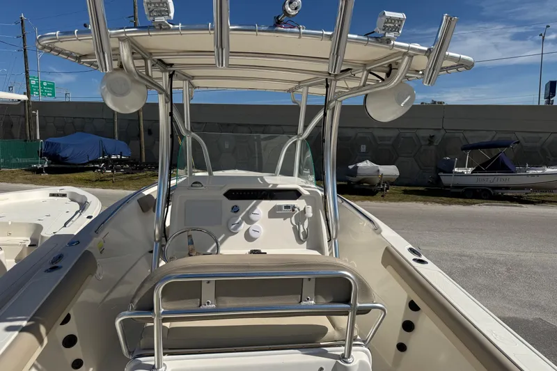 Slide: The Image of 2021 Sailfish 242 CC boat cockpit with steering wheel and T-top under clear sky. - 6