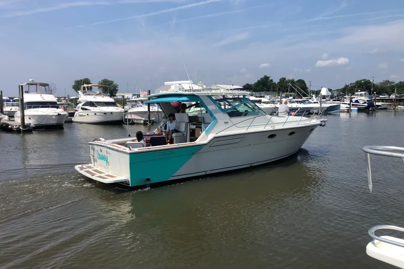 The Image of 1987 Tiara 3600 yacht cruising in a marina with several boats docked nearby. - 2