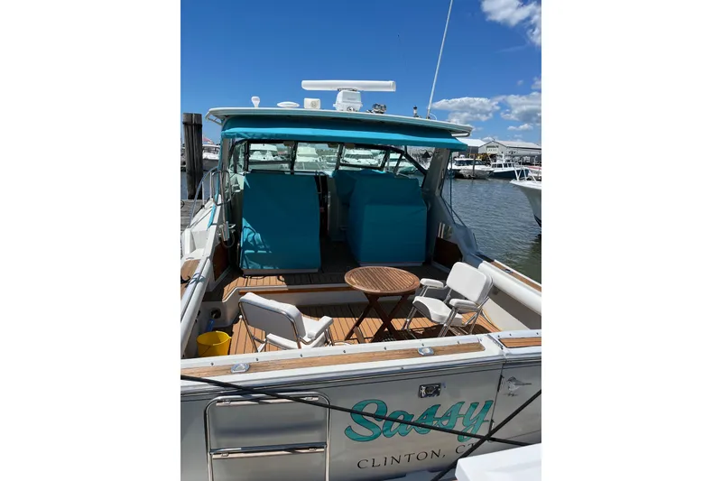 Slide: The Image of 1987 Tiara 3600 boat with blue canopy, docked at marina under clear sky. - 6