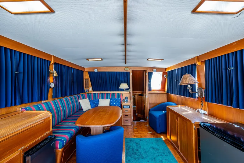 Slide: The Image of Interior of 1990 Grand Banks 46 Classic yacht with blue curtains and wooden furnishings. - 23