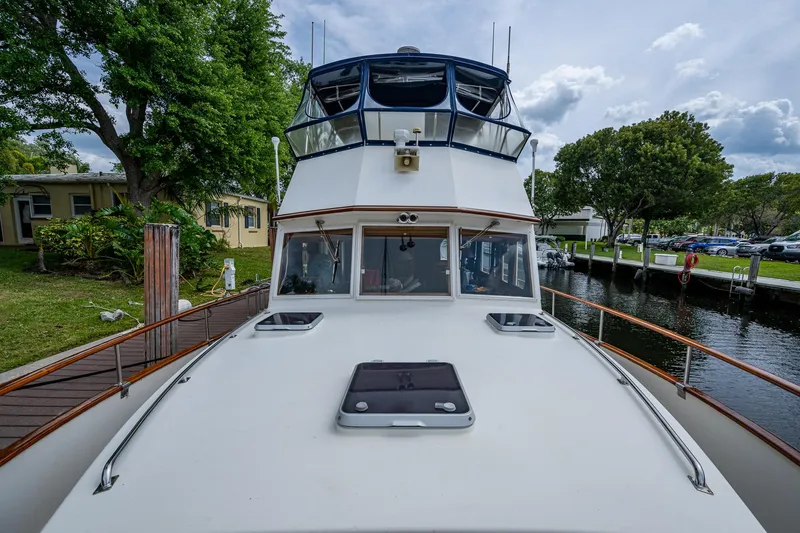 Slide: The Image of Grand Banks 46 Classic 1990 yacht docked by a canal, surrounded by trees and houses. - 8