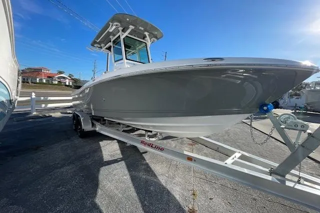 Slide: The Image of 2026 Caymas 24 HB boat on trailer, sleek design, parked outdoors under clear blue sky. - 2