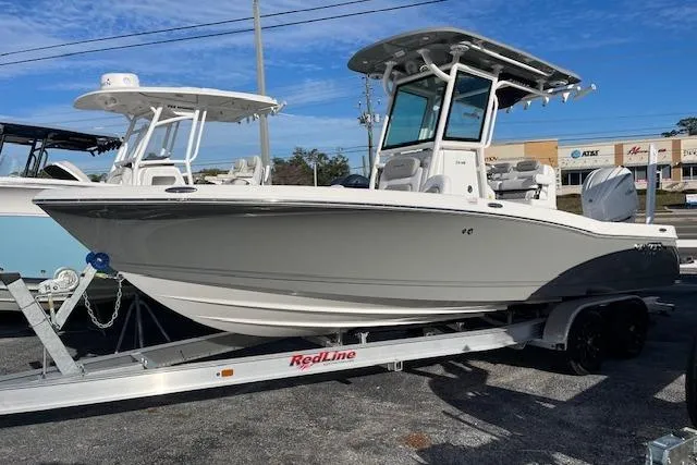 Slide: The Image of 2026 Caymas 24 HB boat on trailer, displayed outdoors at a dealership. - 4