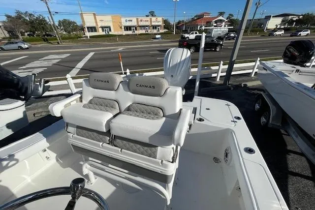 Slide: The Image of 2026 Caymas 24 HB boat with dual seats and outboard motor, parked near a road. - 7
