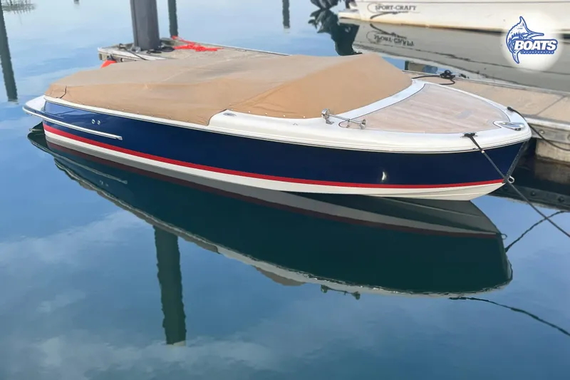 Slide: The Image of 2016 Chris-Craft Capri 21 boat with cover, docked on calm water. - 2