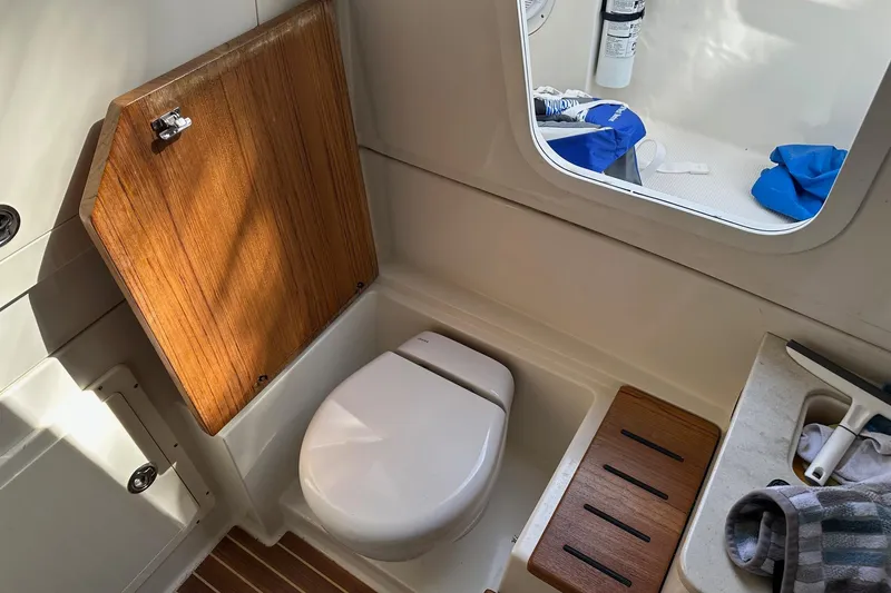 Slide: The Image of 2019 Sailfish 360 CC boat interior with toilet, wooden accents, and window view. - 10