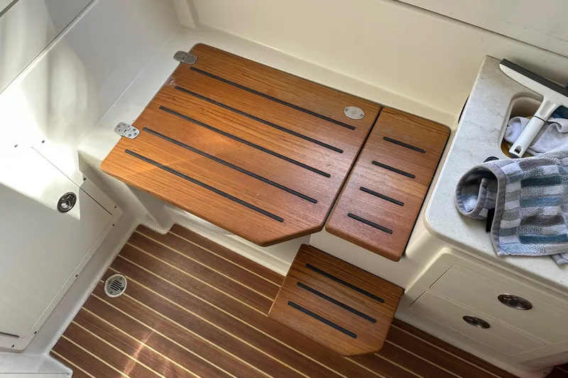 Slide: The Image of 2019 Sailfish 360 CC boat interior with wooden steps and striped towel. - 11