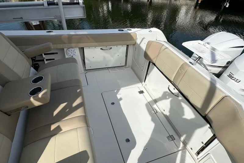Slide: The Image of 2019 Sailfish 360 CC boat interior with beige seating and cup holders, docked by water. - 27