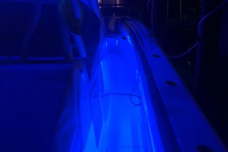 Slide: The Image of 2019 Sailfish 360 CC boat illuminated with blue LED lights at night. - 34