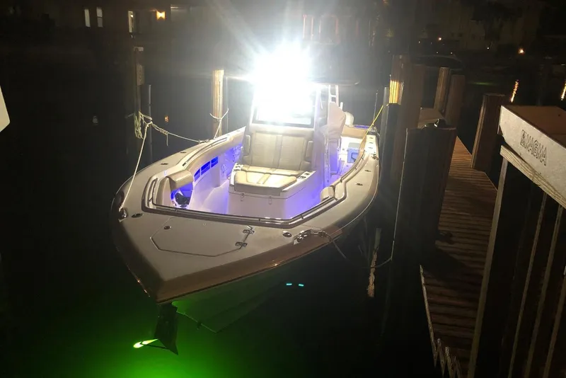 Slide: The Image of 2019 Sailfish 360 CC boat docked at night with bright lights and green underwater glow. - 36