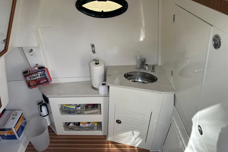 Slide: The Image of 2019 Sailfish 360 CC boat interior with sink, first aid kit, and storage shelves. - 9