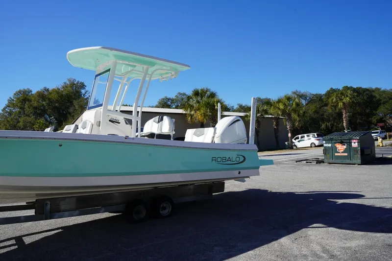 Slide: The Image of 2023 Robalo 246 Cayman boat on trailer, parked outdoors under clear blue sky. - 16