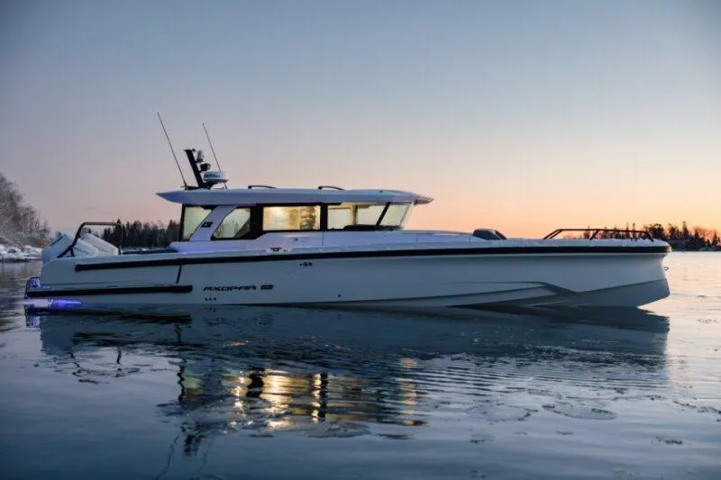 Slide: The Image of 2026 Axopar 38 Cross Cabin boat on calm water at sunset. - 2