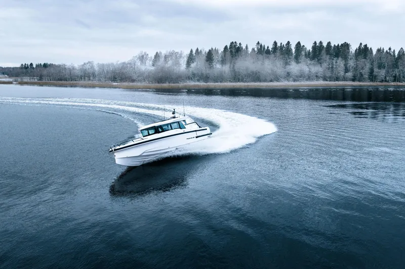 Slide: The Image of 2026 Axopar 38 Cross Cabin boat navigating a serene, icy lake. - 3