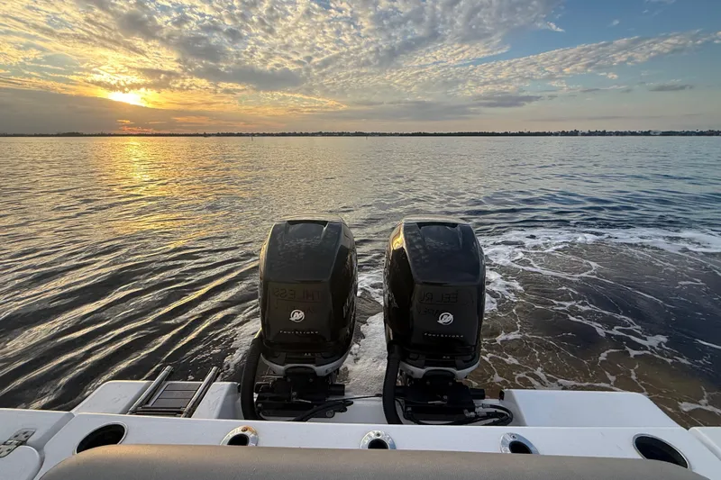 Slide: The Image of 2022 Sportsman Open 322 Center Console boat with dual engines at sunset on calm waters. - 12