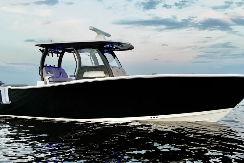 Slide: The Image of 2022 Sportsman Open 322 Center Console boat on calm water at sunset. - 2
