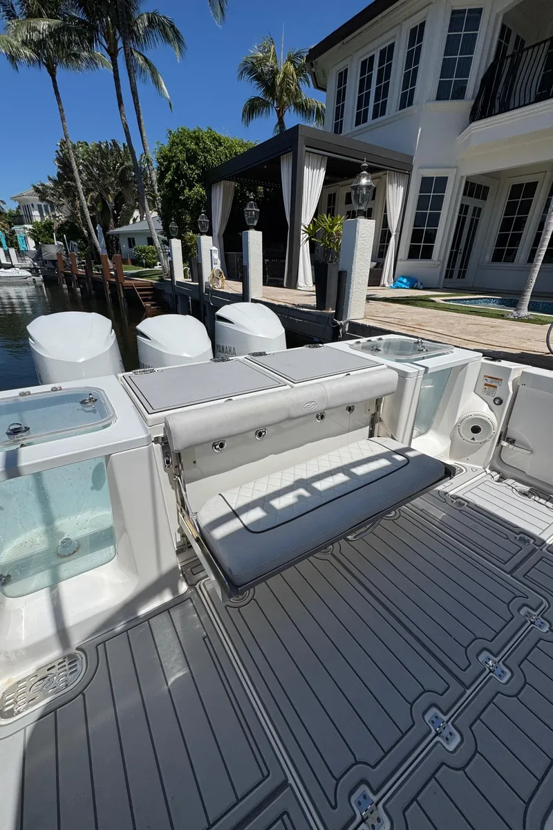 Slide: The Image of 2020 Sea Fox 368 Commander boat with spacious deck and seating, docked by a waterfront home. - 8