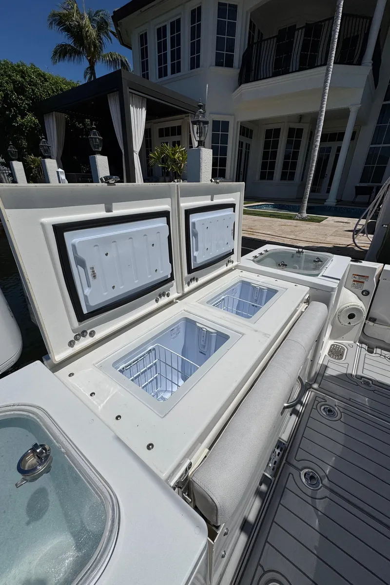 Slide: The Image of 2020 Sea Fox 368 Commander boat with open storage compartments, docked near a luxury house. - 9