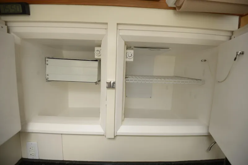 Slide: The Image of 1995 Lagoon TPI interior storage compartments with shelves and temperature gauge. - 12